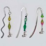 Photo of metal bookmarks available for purchase. This set shows 3 different shiny metal bookmarks with a beaded hanging dangle in various colors with a small monkey shaped charm at the bottom.