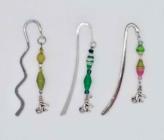 Photo of metal bookmarks available for purchase. This set shows 3 different shiny metal bookmarks with a beaded hanging dangle in various colors with a small monkey shaped charm at the bottom.