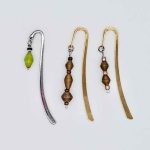 Photo of metal bookmarks available for purchase. This set shows 3 different shiny metal bookmarks with a beaded hanging dangle in various colors of small beads.