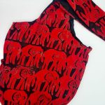 Sling bag in all over red elephants on a very dark background.