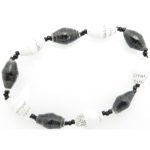 Black and white bead bracelet closeup, The stretch bracelet contains 10 paper beads separated by seed beads.