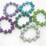 Grouping of6 round bead stretch bracelets in various shades of blues, greens and one purple.