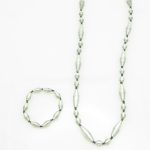 Women's matching beaded necklace and bracelet set in shiny silver small & large oval bead pattern. Handcrafted with paper beads by Ugandan women artisans.