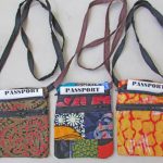 Photo of 3 black strapped colorful cloth passport holders that are available to purchase. Choose your color: green/red; multi-color; or bright orange/red patterned.