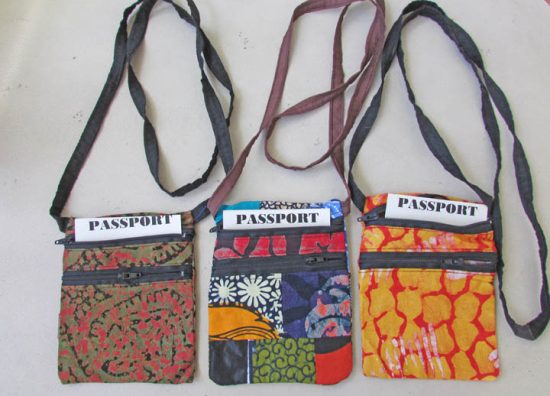 Photo of 3 black strapped colorful cloth passport holders that are available to purchase. Choose your color: green/red; multi-color; or bright orange/red patterned.