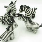 Photo of 7 mini stuffed animal zebras available to purchase. The zebras come in several patterns of black & white stripes.