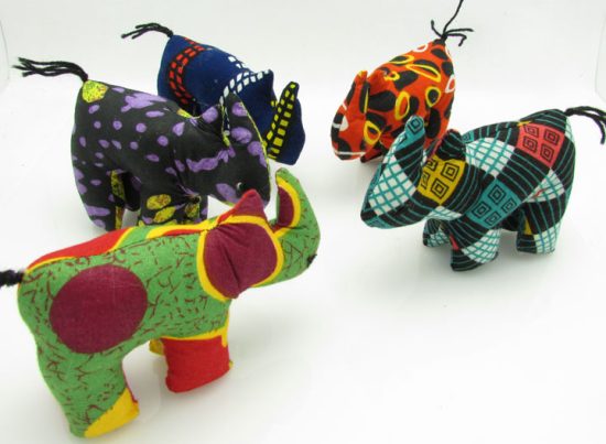 Photo of 7 mini stuffed animal rhinos available to purchase. The rhinos come in a variety of different colors/patterns of African kitenge cloth.