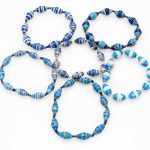 Photo of a grouping of 6 basic single strand stretch bracelets. Each bracelet is demonstrating the different kinds of blue striped patterns that might be available for purchase.