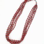 Photo of red 5-strand beaded necklace that is available to purchase. The necklace contains small bi-cone shaped beads in varying shades of blue with a barrel type fastener at the top.