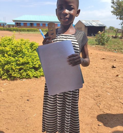 Young Ugandan child with letter writing materials.